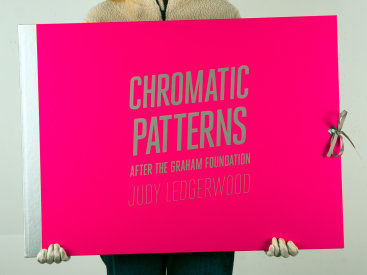 Deluxe edition portfolio: “Chromatic Patterns After the Graham Foundation”, 2014. Three lithographs with relief and aluminum dust by Judy Ledgerwood and a poem by John Yau, housed in custom portfolio case. Yau’s poem, “26 Letters for Judy Ledgerwood”, is silkscreened in silver ink. Poem and prints are 22″ x 30″. The portfolio case is covered in pink fabric with title and colophon silkscreened in silver. Grommet and grosgrain ribbon closure. The deluxe edition is limited to 8 sets.
